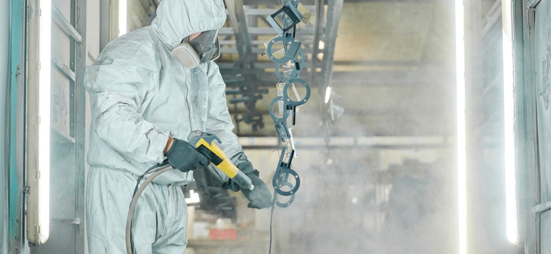 Person wearing protective gear using welding equipment in an industrial setting.