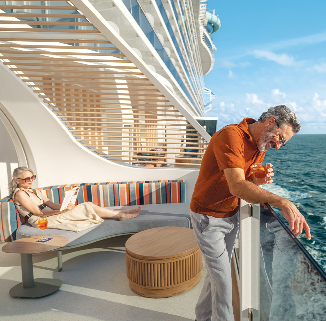 A senior man with gray hair and glasses leaning on a cruise ship railing, holding a drink, near the ocean with a blue sky; a woman in sunglasses and a light dress relaxing on striped outdoor lounge seating with a drink nearby.