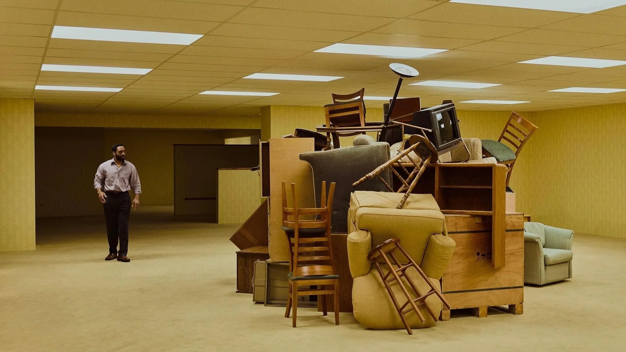 Man standig in room with pile of furnature