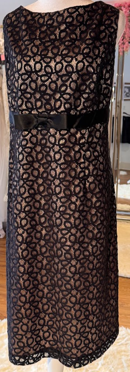 Long black lace dress with a sheer pattern and a black ribbon belt at the waist.