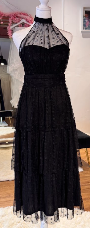 Black halter dress on a mannequin with sheer polka dot overlay and tiered skirt.