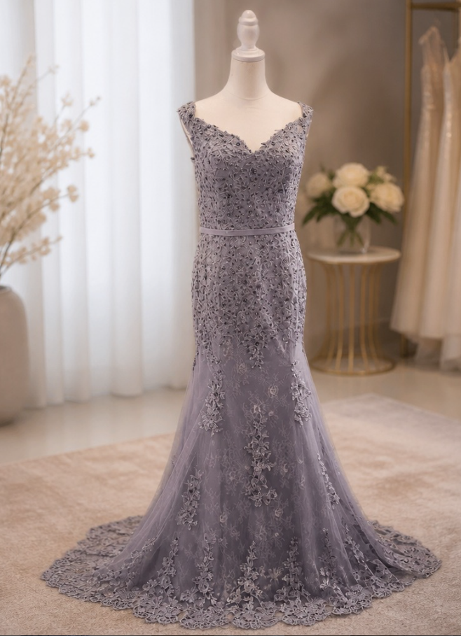 Gray lace wedding dress on a mannequin in a bridal boutique with floral decor and curtains in the background.