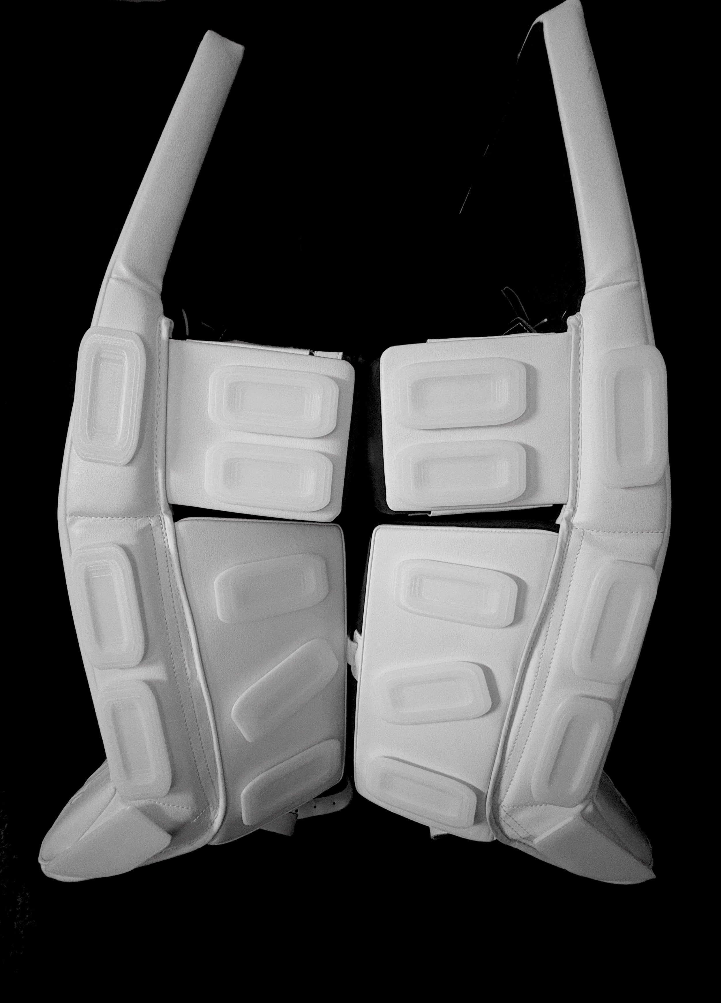 A pair of white hockey goalie leg pads with goalie sliders installed, black background.