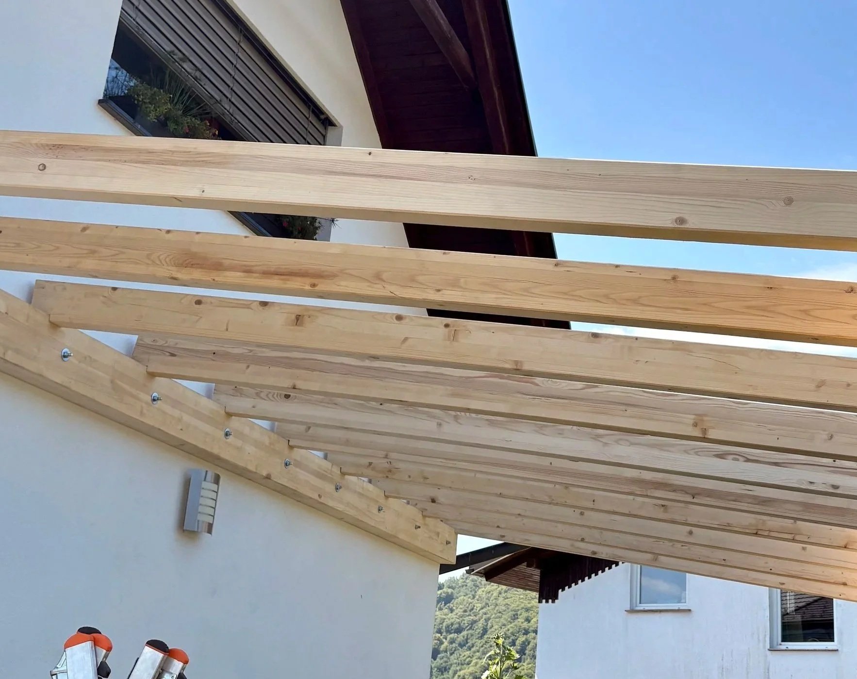 Lesena pergola integrirana v fasado hiše.