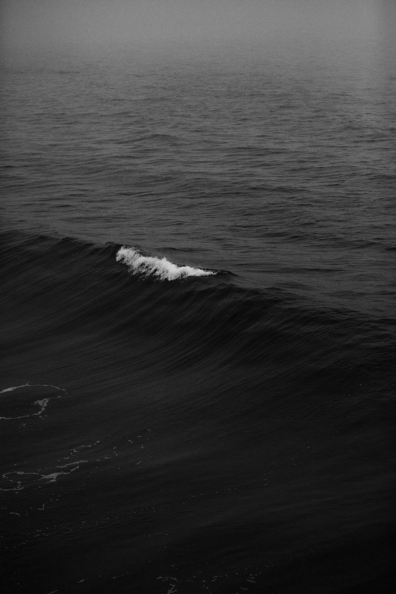 Black and white photo of ocean waves with overcast sky