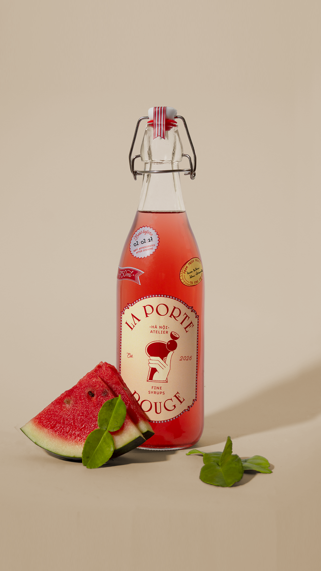 A bottle of La Porte Rouge fine syrup drink, with a slice of watermelon and some green leaves in front of it.
