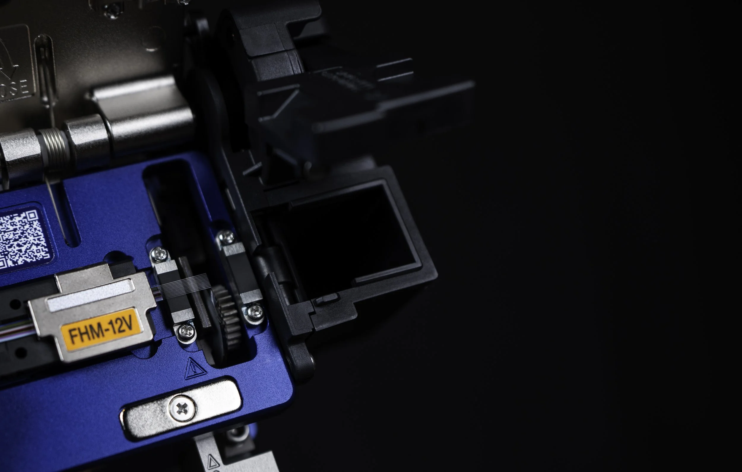 Close-up of a sumitomo fiber optic cleaver against a black background.