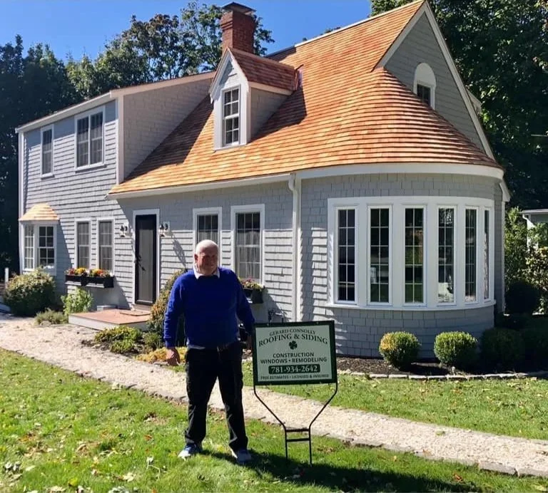 A man standing in front of a newly renovated house with a construction sign on the lawn.