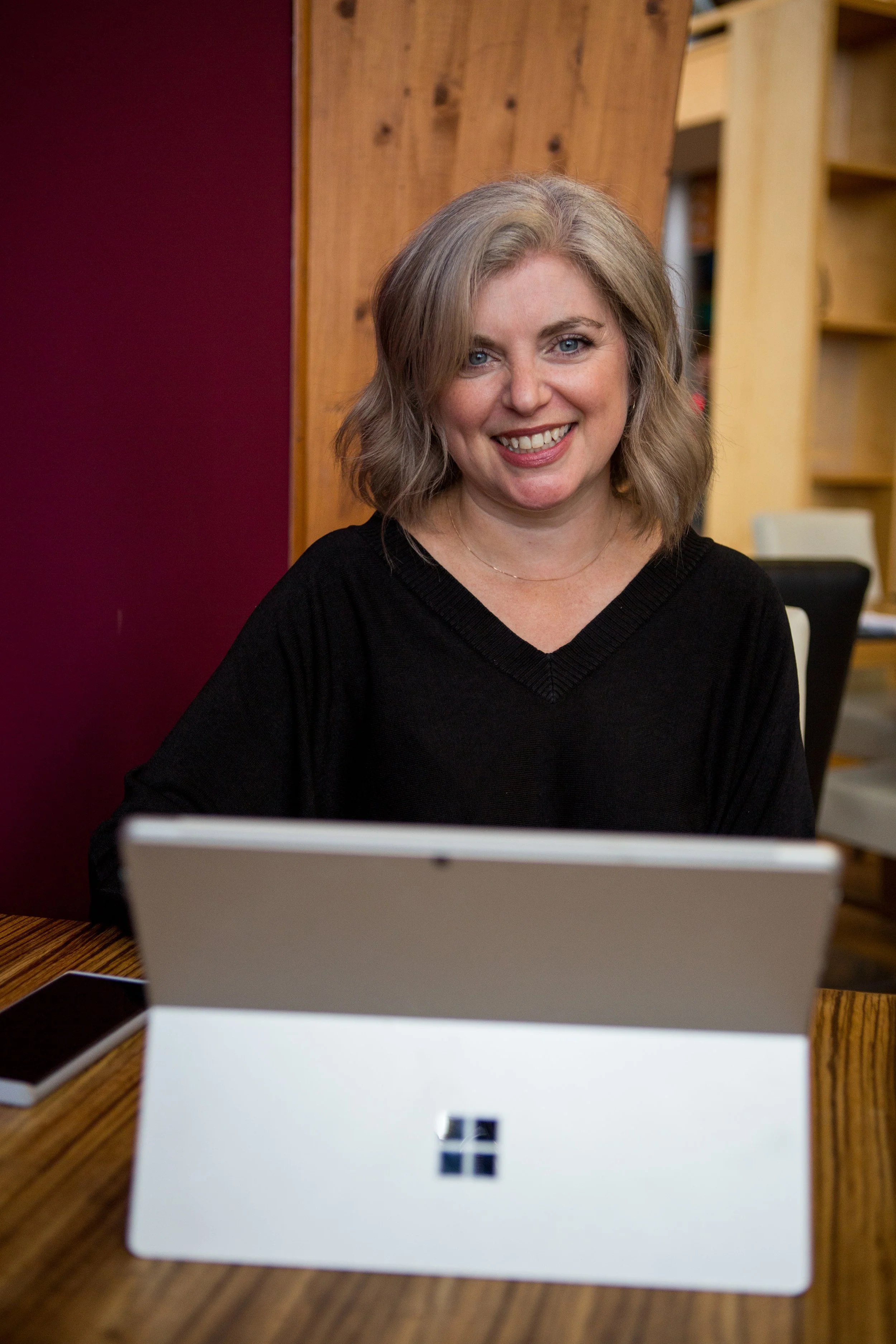 A professinal woman working as an HR Consultant, smiling at the camera with a laptop in front of her
