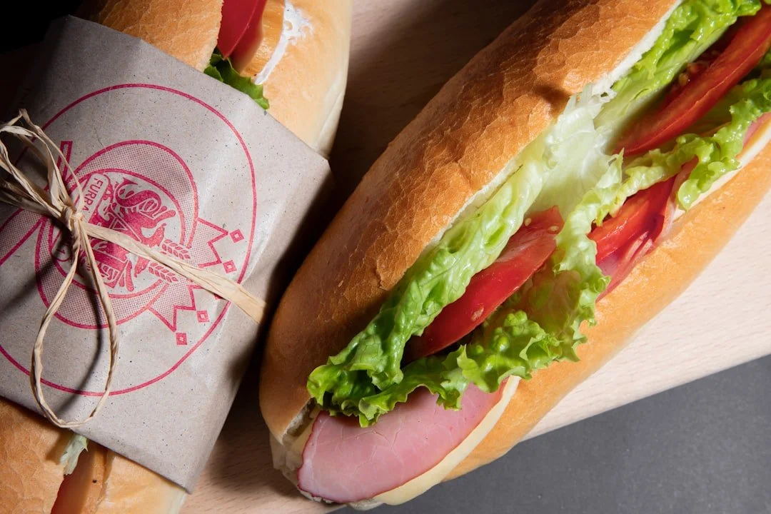 A fresh submarine sandwich with lettuce, tomato, ham, and cheese in a baguette-style bun.