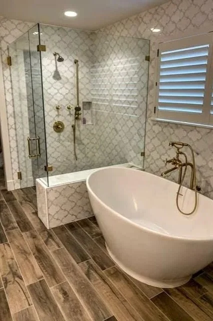 Marble arabesque tile shower with freestanding tub and wood look plank floor in Bartlett IL
