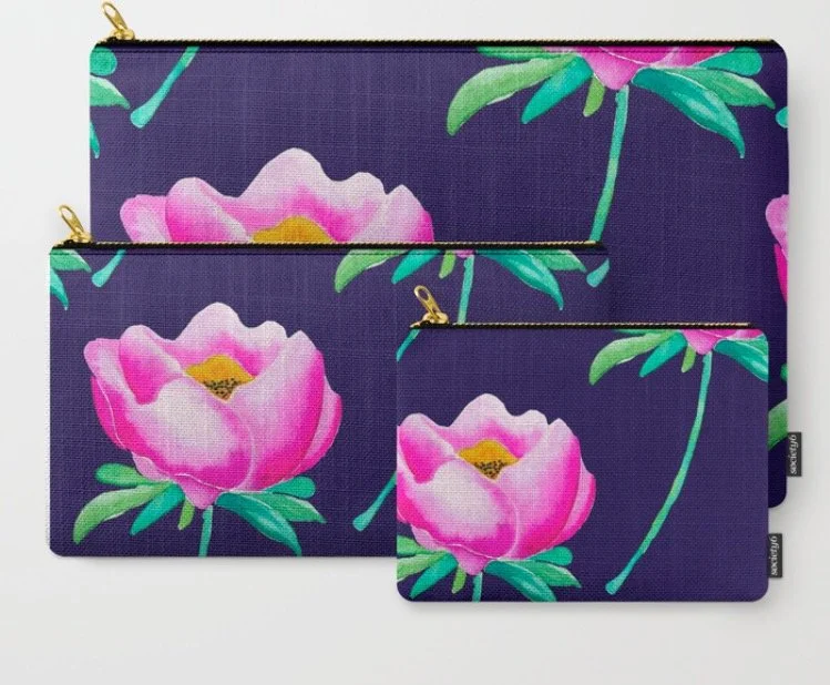 Three fabric zippered pouches with a purple background and pink floral pattern, arranged in size order from largest to smallest.