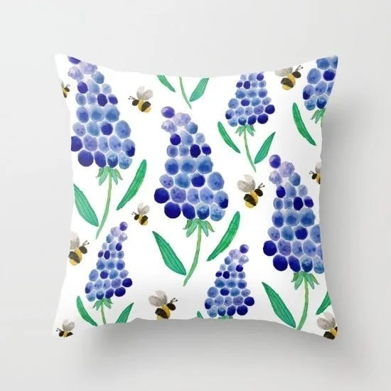 Square pillow with a pattern of purple hyacinth flowers, green leaves, and buzzing bees on a white background.