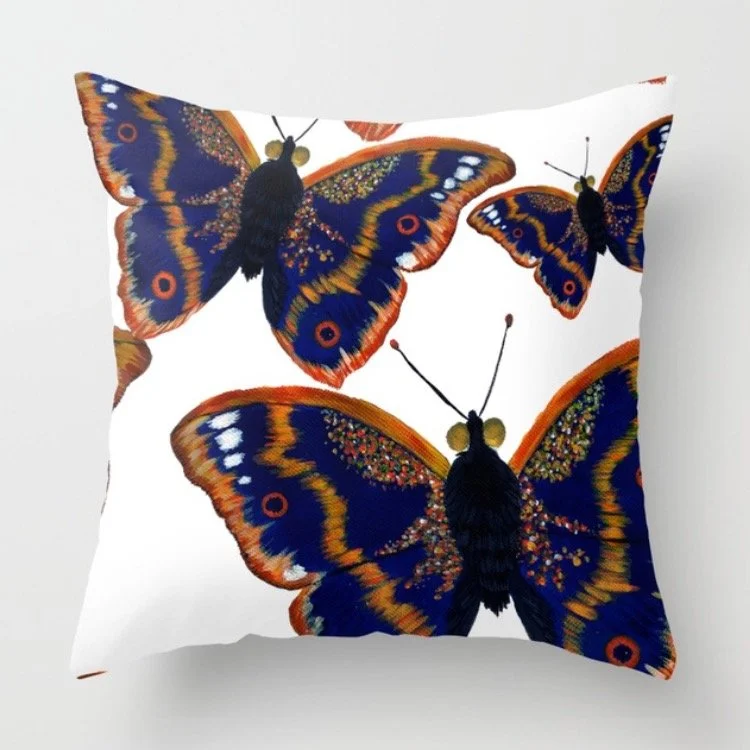 Decorative pillow with a white background featuring colorful butterfly illustrations in shades of blue, orange, black, and gold.