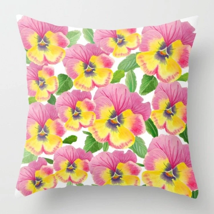 Decorative pillow with a floral pattern featuring yellow and pink pansies with green leaves.
