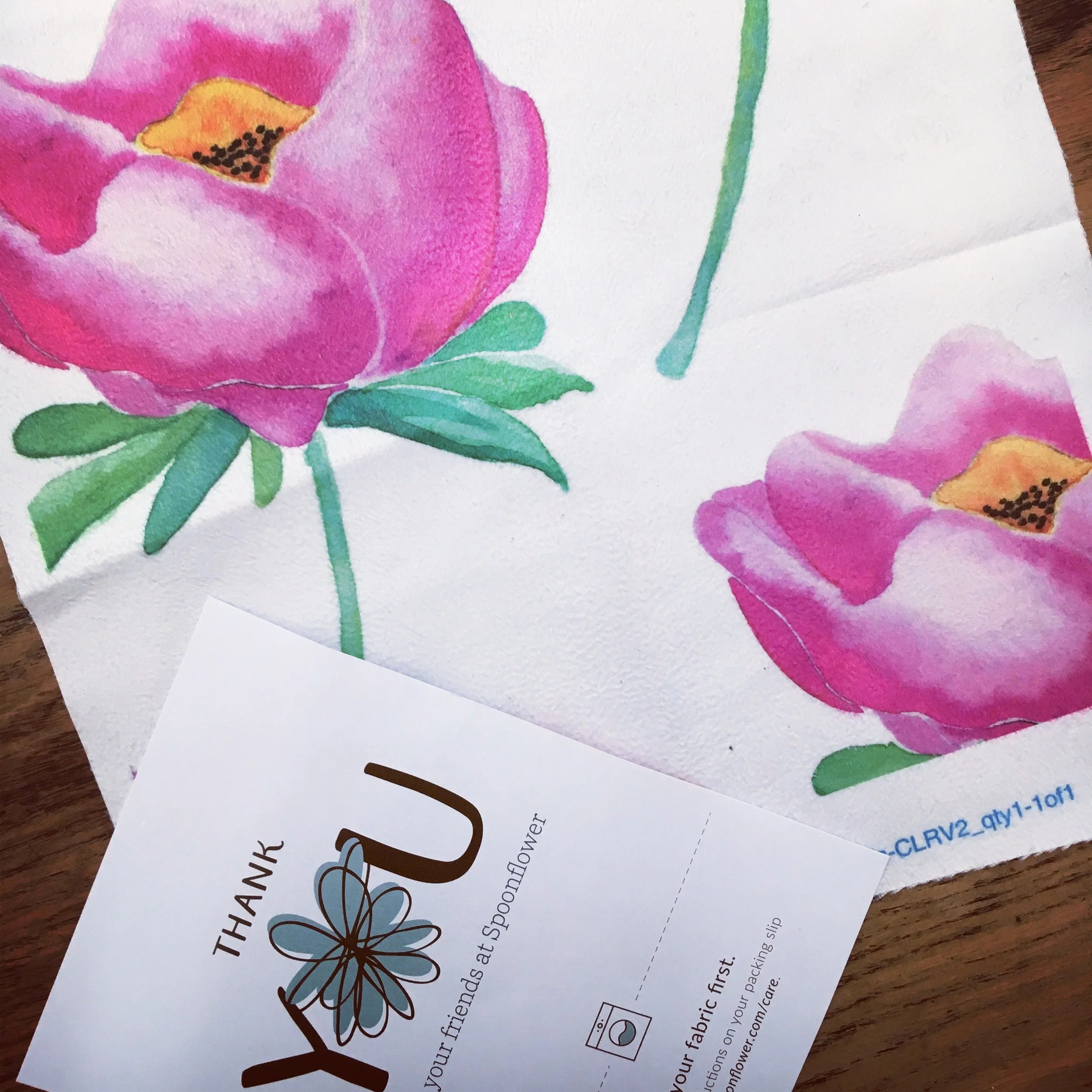 Close-up of a watercolor painting of pink peonies with green leaves and stems, alongside a thank you card with a flower illustration.