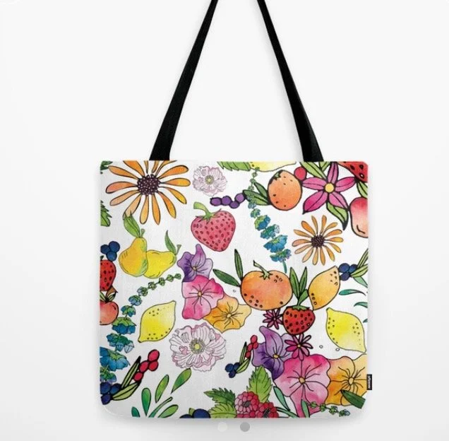 Colorful tote bag with a floral and fruit pattern, featuring strawberries, peaches, lemons, and various flowers, with black handles.