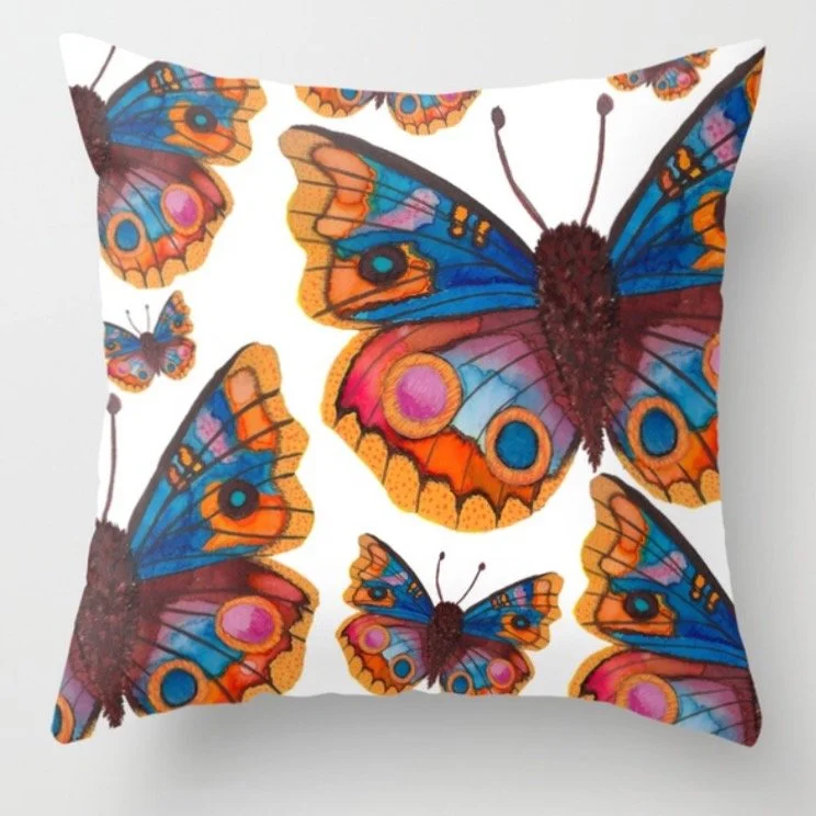 Decorative pillow with vibrant, colorful butterfly print featuring blue, orange, pink, and yellow wings on a white background.