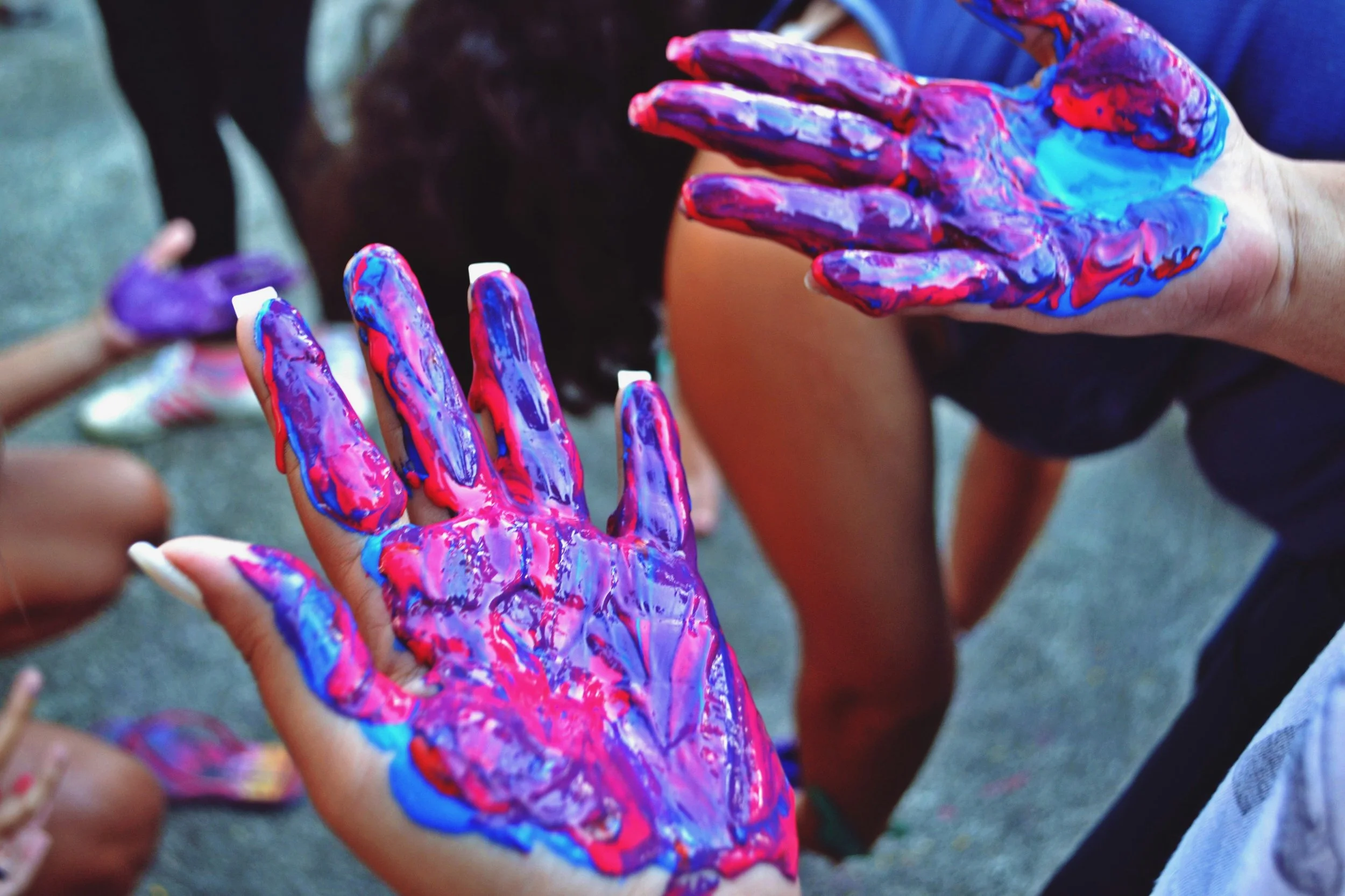 Children with painted hands playing together outdoors.