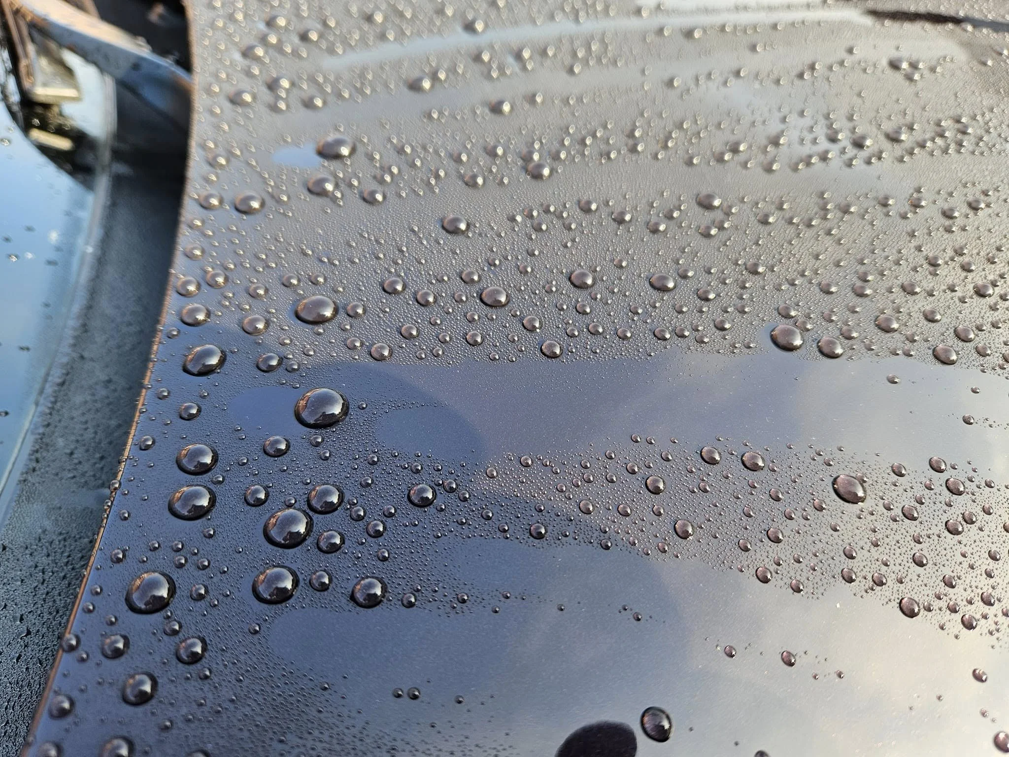 Close-up of a metallic surface with water droplets scattered across it.