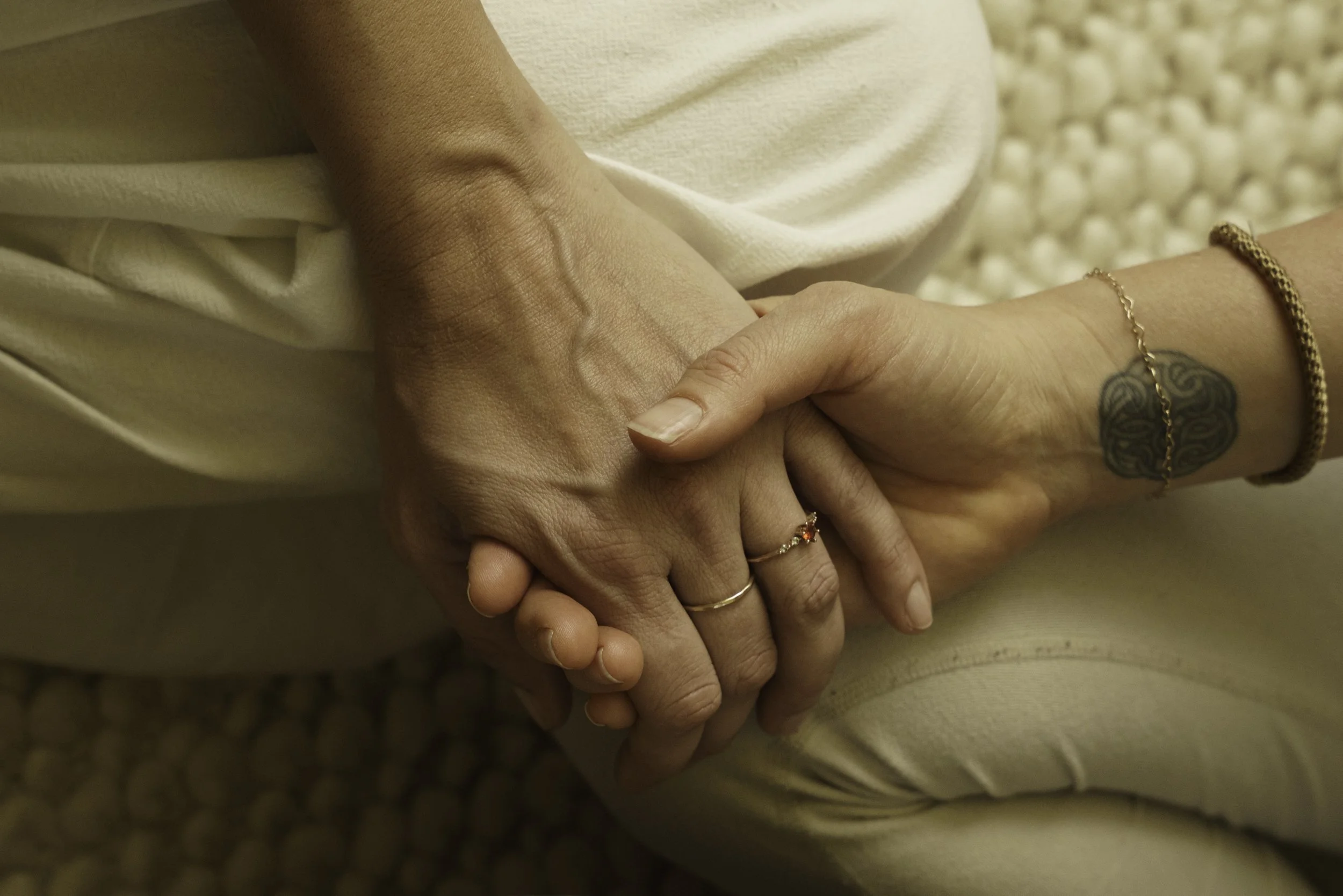 A retreat facilitator holding a participant's hand to provide compassionate support during a guided psilocybin experience.
