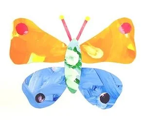 Colorful paper butterfly craft with orange, yellow, blue, and green paper wings and googly eyes.