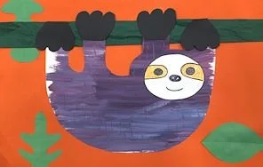 A cartoon sloth hanging upside down from a tree branch with a white face and large eyes, set against an orange background with green leaves.