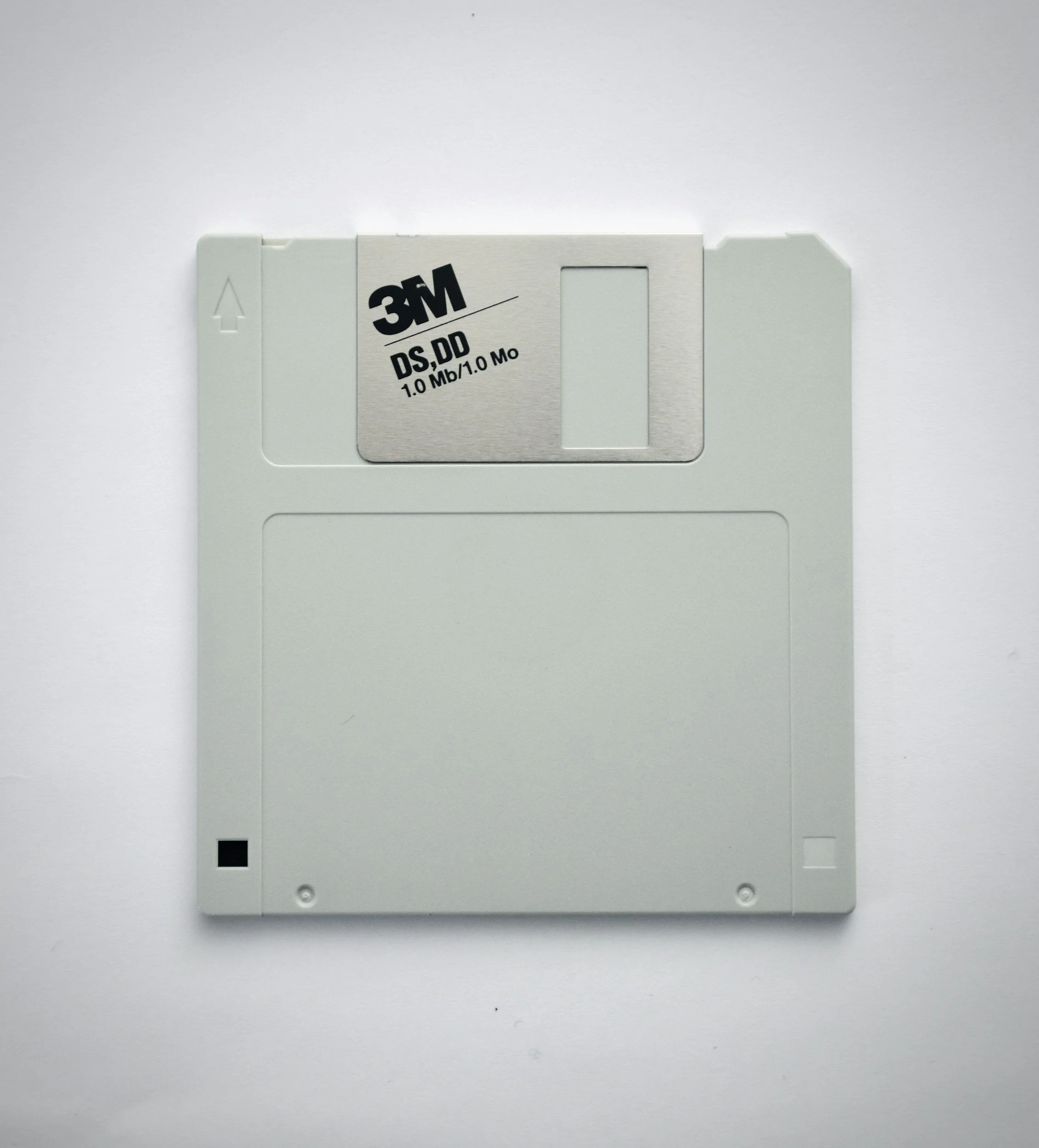 A 3M floppy disk with a white plastic casing and a metal sliding cover, labeled '3M DS,DD 1.0 MB/1.0 Mo'.