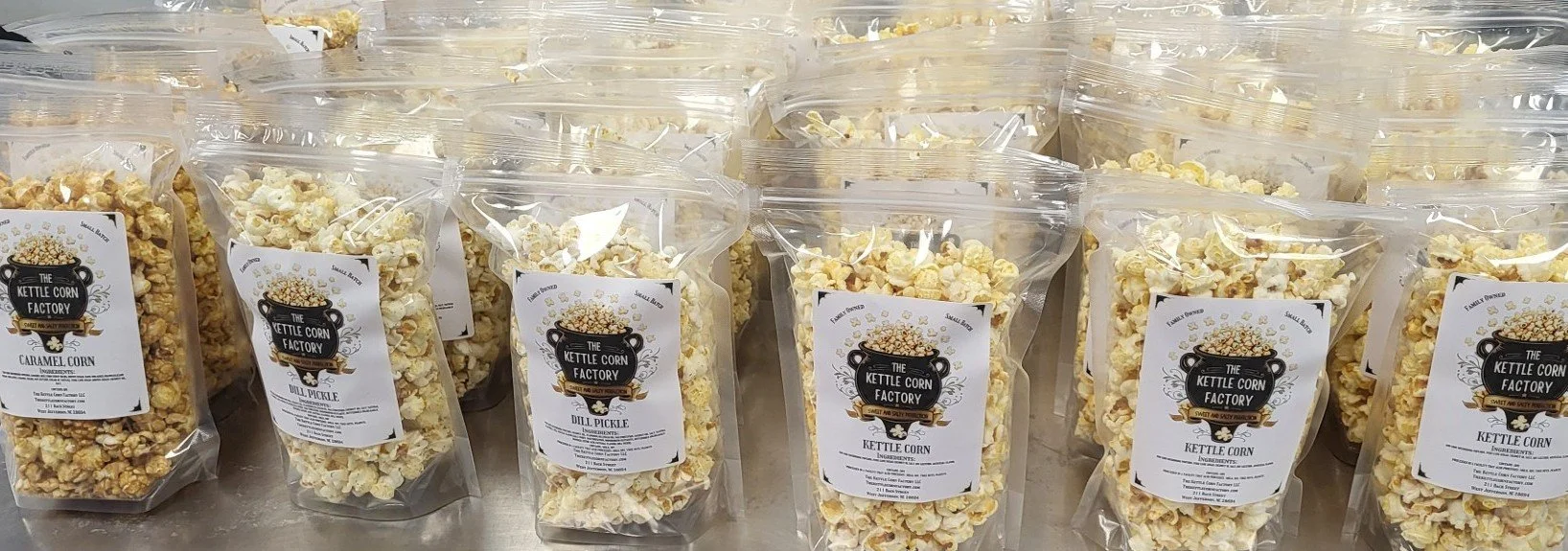 Multiple packages of caramel corn, labeled as "The Kettle Corn Factory" with flavors like dill pickle, on a store shelf.
