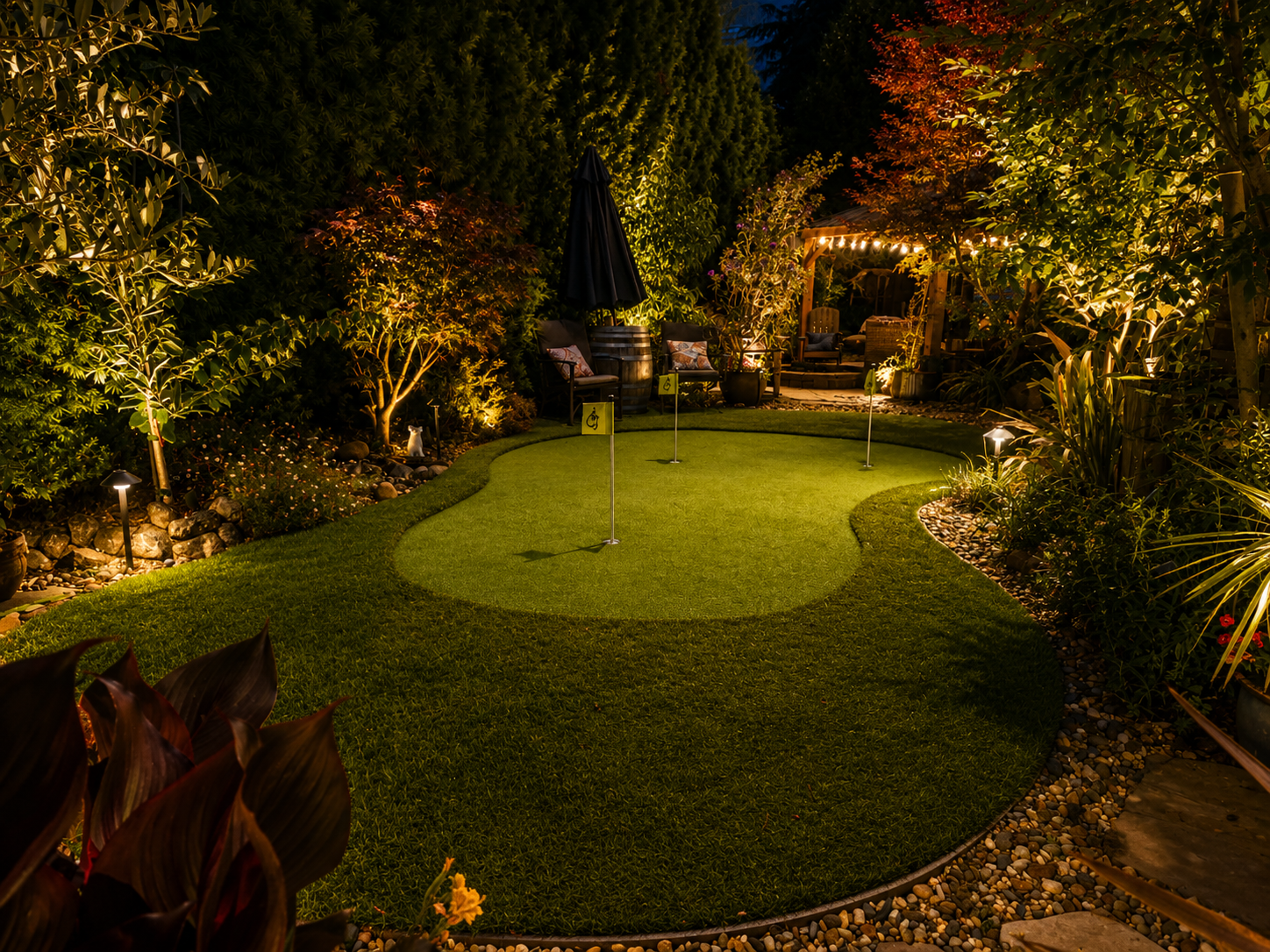 Night view of a backyard with a putting green for golf, surrounded by trees, shrubs, and garden lights, with signs indicating a wheelchair accessible area.