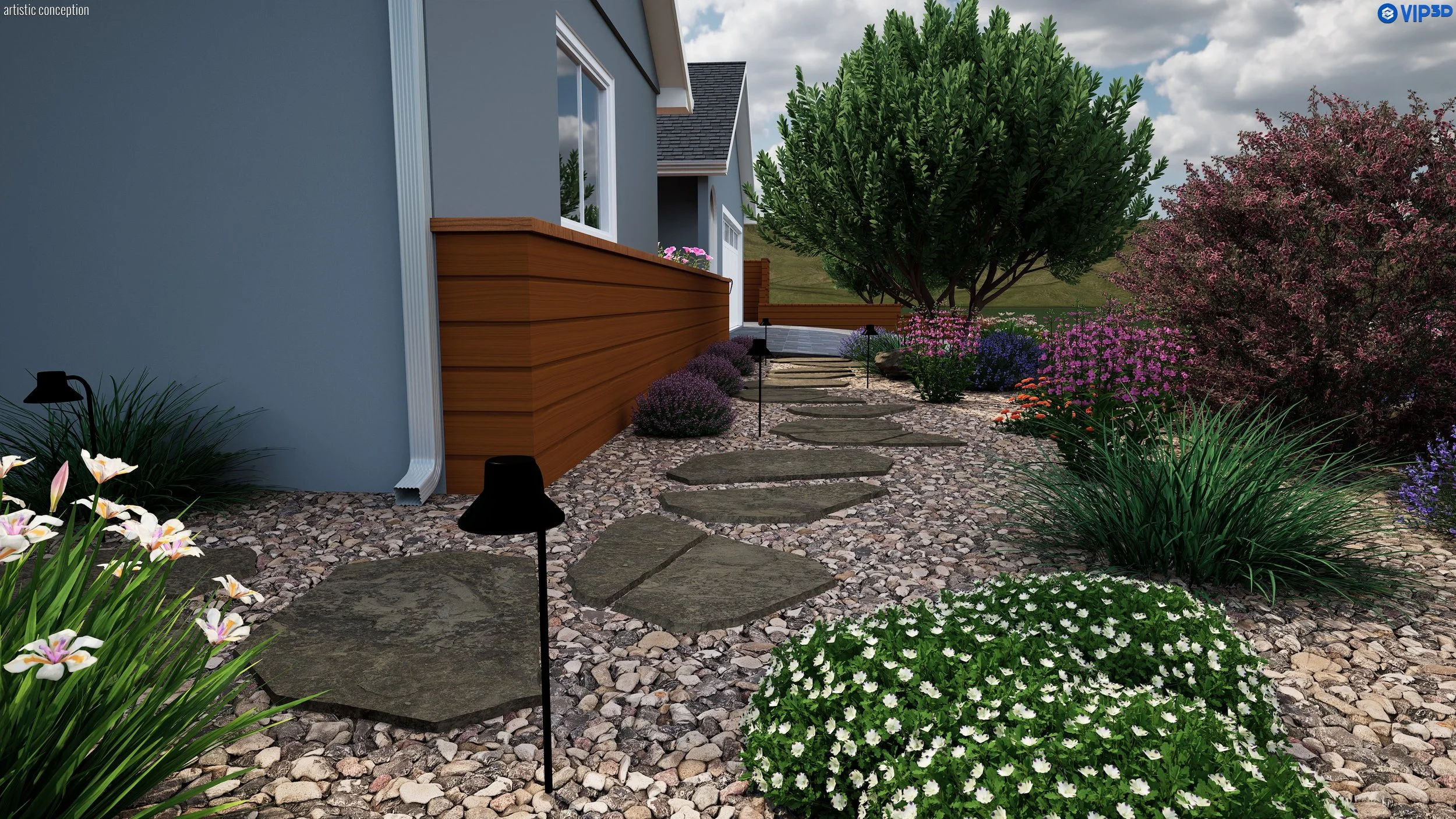 A landscaped backyard garden with a stone pathway leading to a wooden deck, surrounded by various flowering plants and bushes, with a house wall and window on the left, and a green hill in the background under a partly cloudy sky.