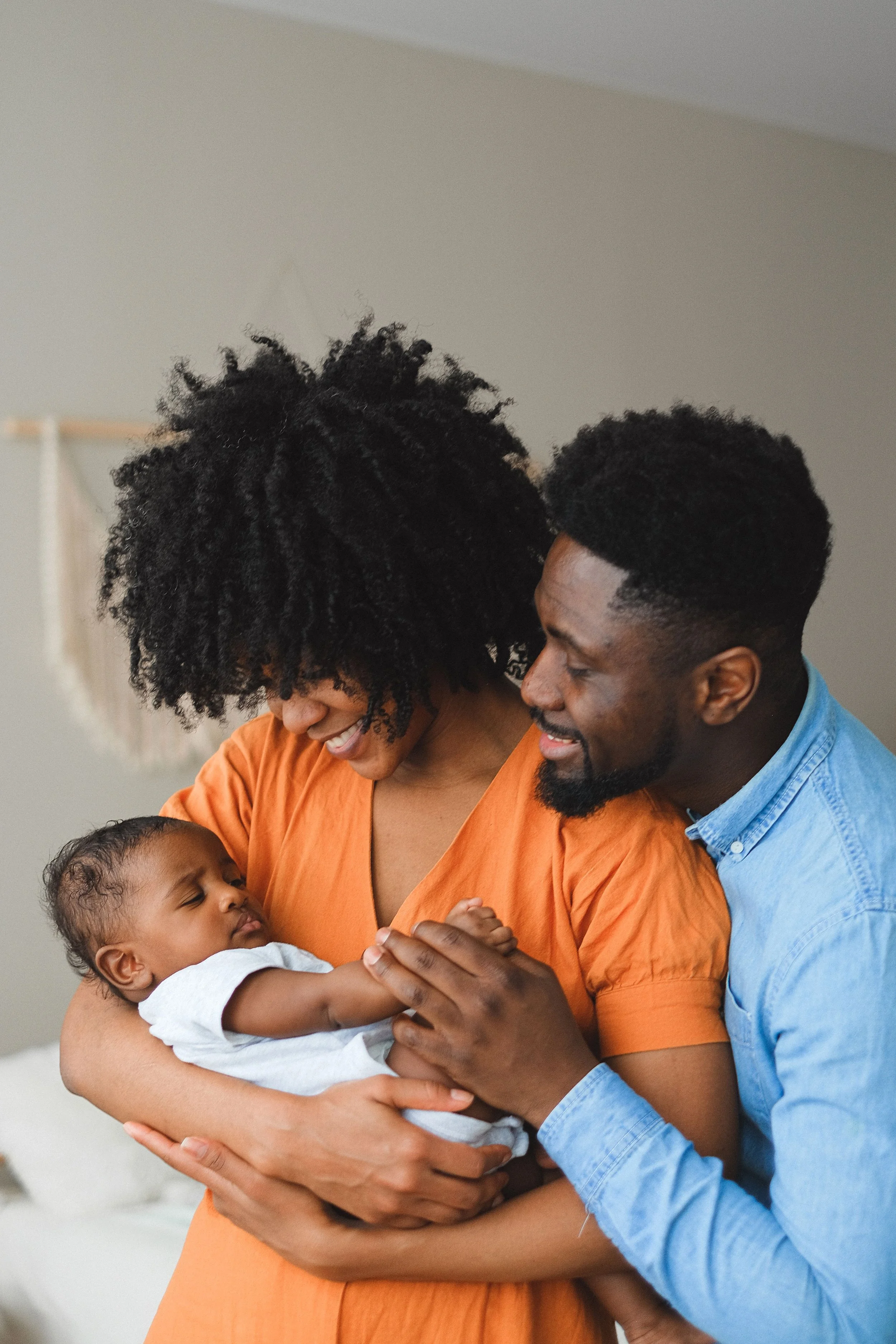 A mother and father embracing their newborn, supported by The Mothers Village postpartum doula team.