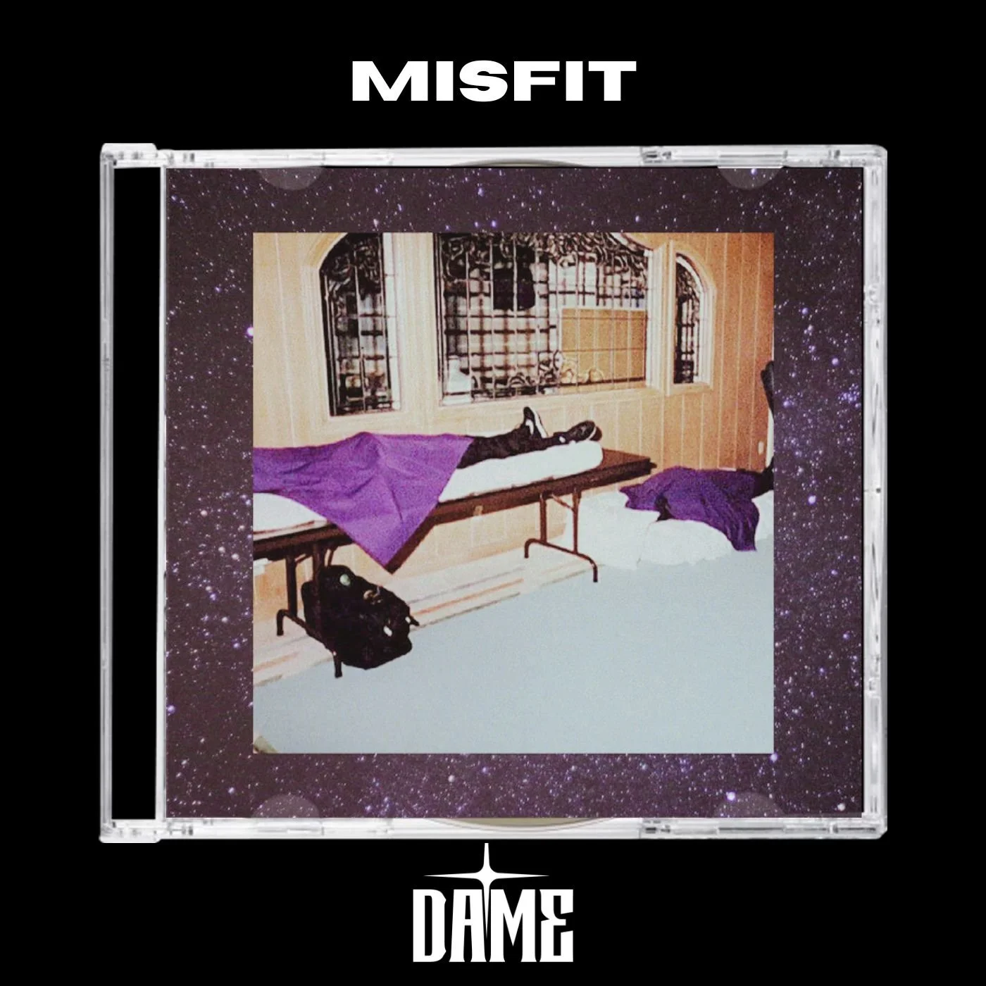 A poster with the title 'MISFIT' at the top and the word 'DAME' at the bottom, featuring a photograph of a room with a bed, purple blanket and pillow, and a person lying face down underneath the blanket. The room has wooden walls, windows with iron grilles, and a black bag on the floor.