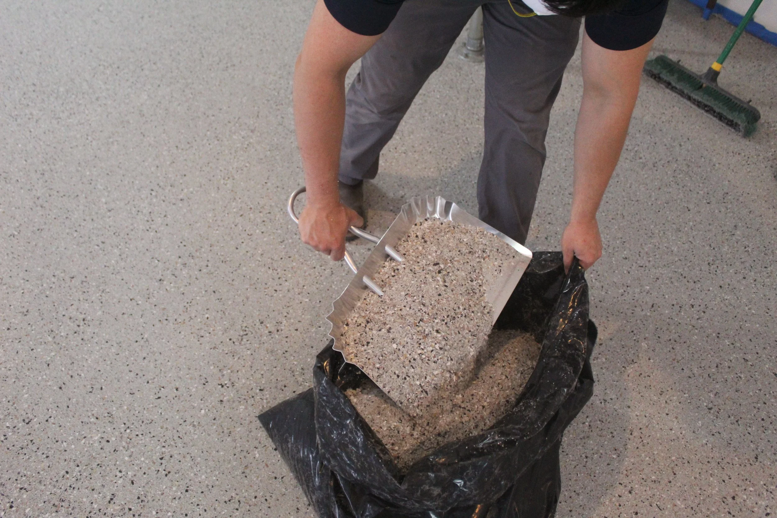 exodus epoxy and flooring employee collecting excess flake after scraping