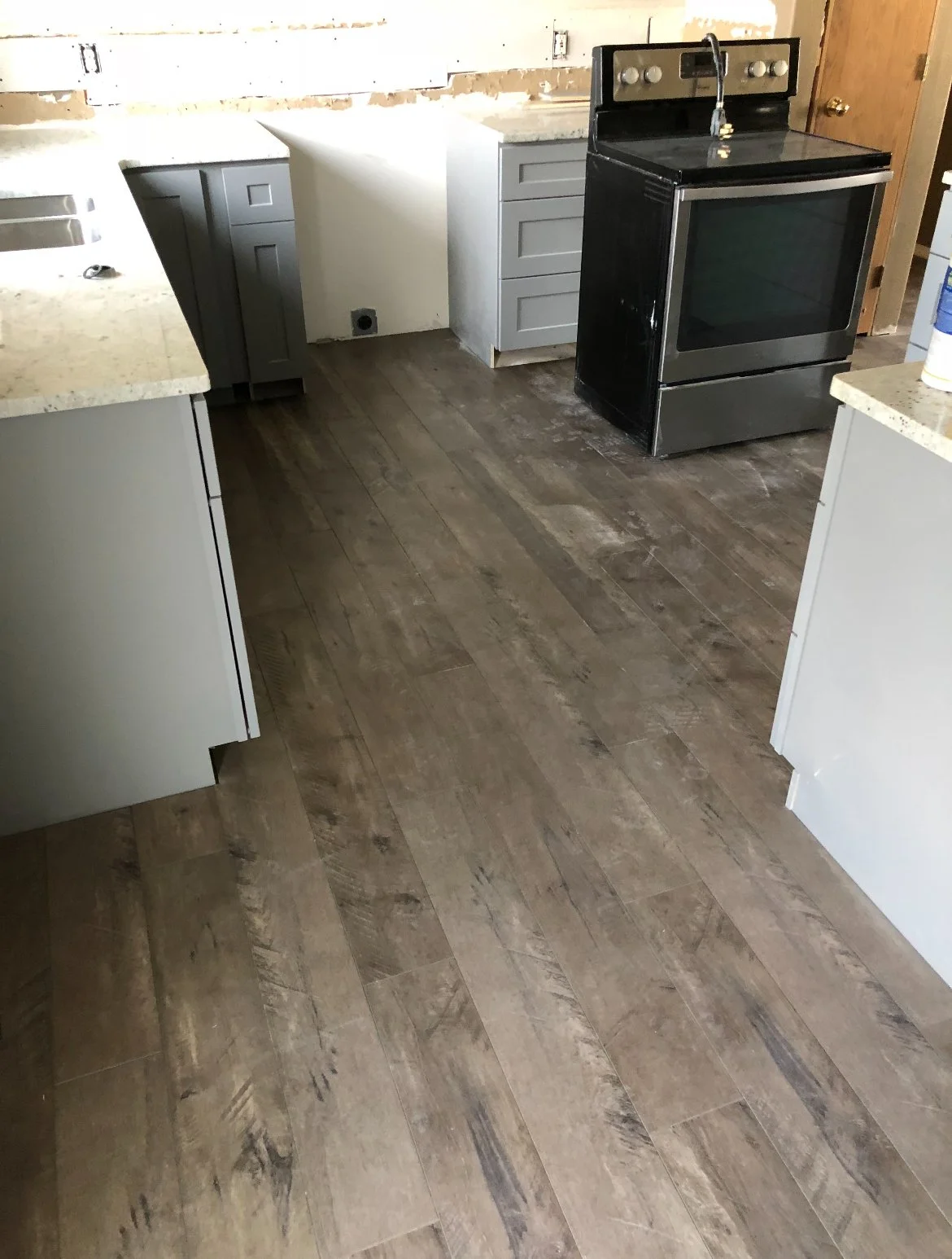 Kitchen with brown wood-look flooring, light gray cabinets, and black stove.