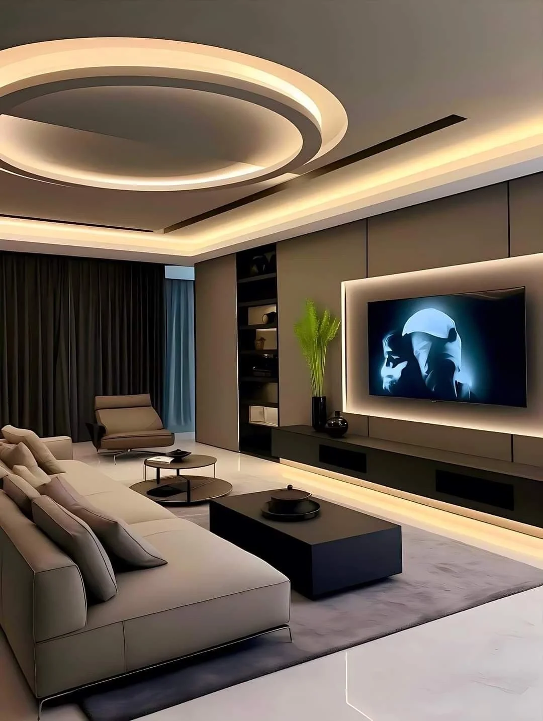Modern living room with beige sofa, black coffee table, armchair, built-in entertainment center, large flat-screen TV, decorative plants, dark curtains, and recessed ceiling lighting.