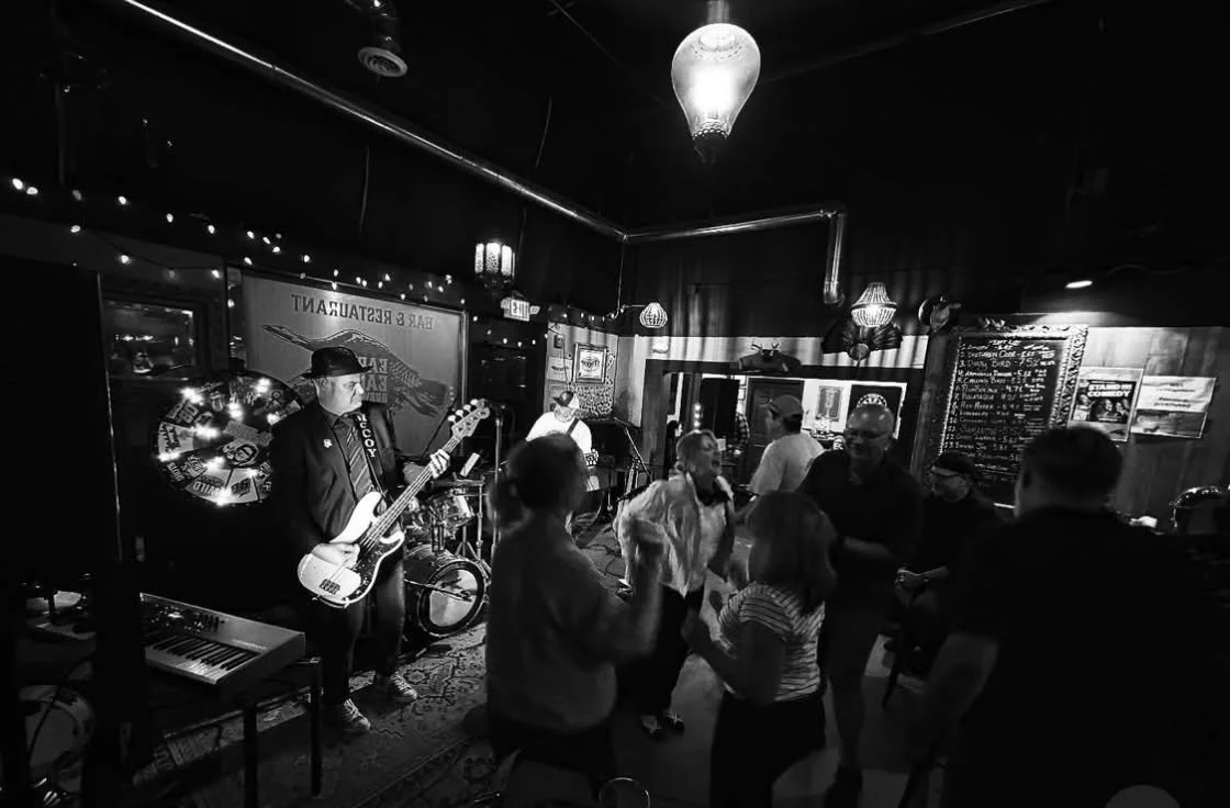 People dancing and enjoying live music in a cozy bar or restaurant with a band playing on stage.