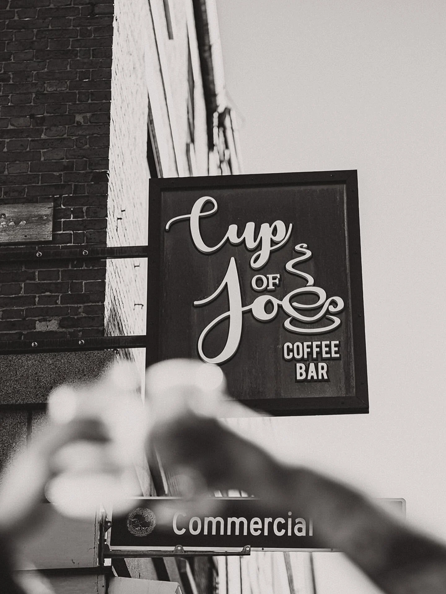 A sign advertising a coffee shop called "Cup of Joe" with the words "Coffee" and "Bar" beneath it.