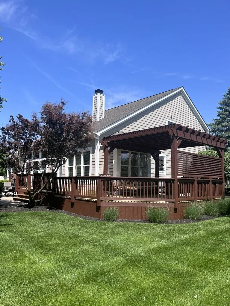 A house with beige siding and a gray roof, featuring a large wooden deck with a pergola and outdoor furniture. Host a cookout or just take a beat for some fresh air. Decks are a necessary addition to any Central Ohio home.