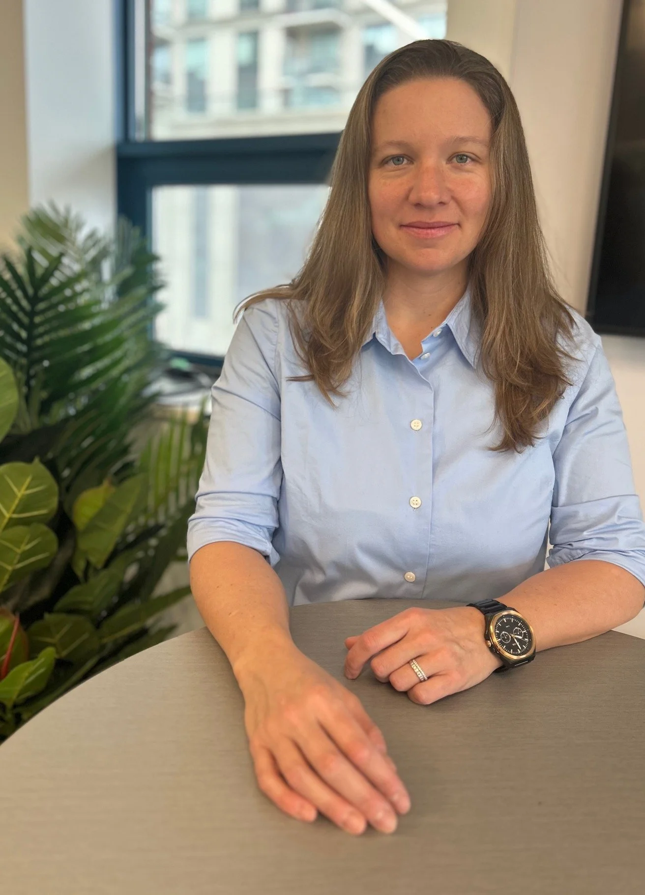 A portrait of Lindsey Elliott, Merchandising Consultant and former global VP. Standing at a desk, this image highlights the corporate authority and strategic business logic she brings to her fractional leadership services.