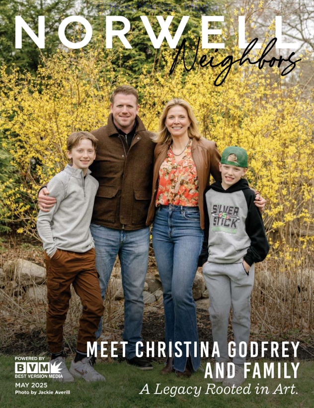 Family photo of a woman, two boys, and a man standing outdoors in front of yellow flowering bushes.