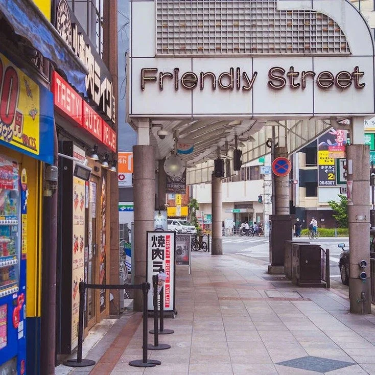 The entrance of a shopping street in Osaka, with signs and shops, captured during slow travel.