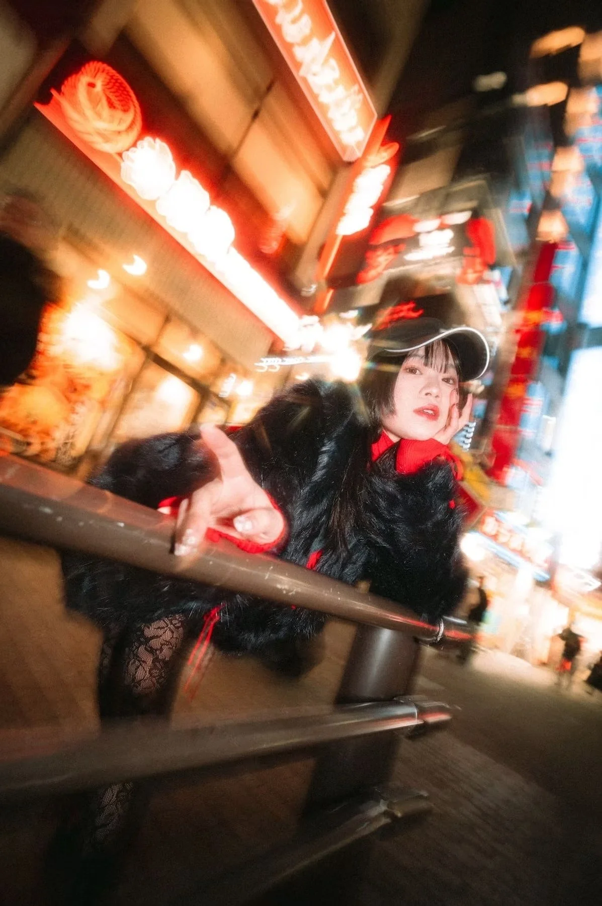 A young woman strikes a carefree pose on a bustling street, surrounded by the energy of neon lights and motion blur. Her laid-back style and lively expression capture the essence of city nightlife.