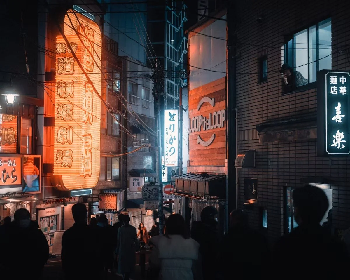 Cyberpunk night street scene in an Shibuya city with illuminated vertical neon signs in Japanese, people walking, and a woman looking out of a window.