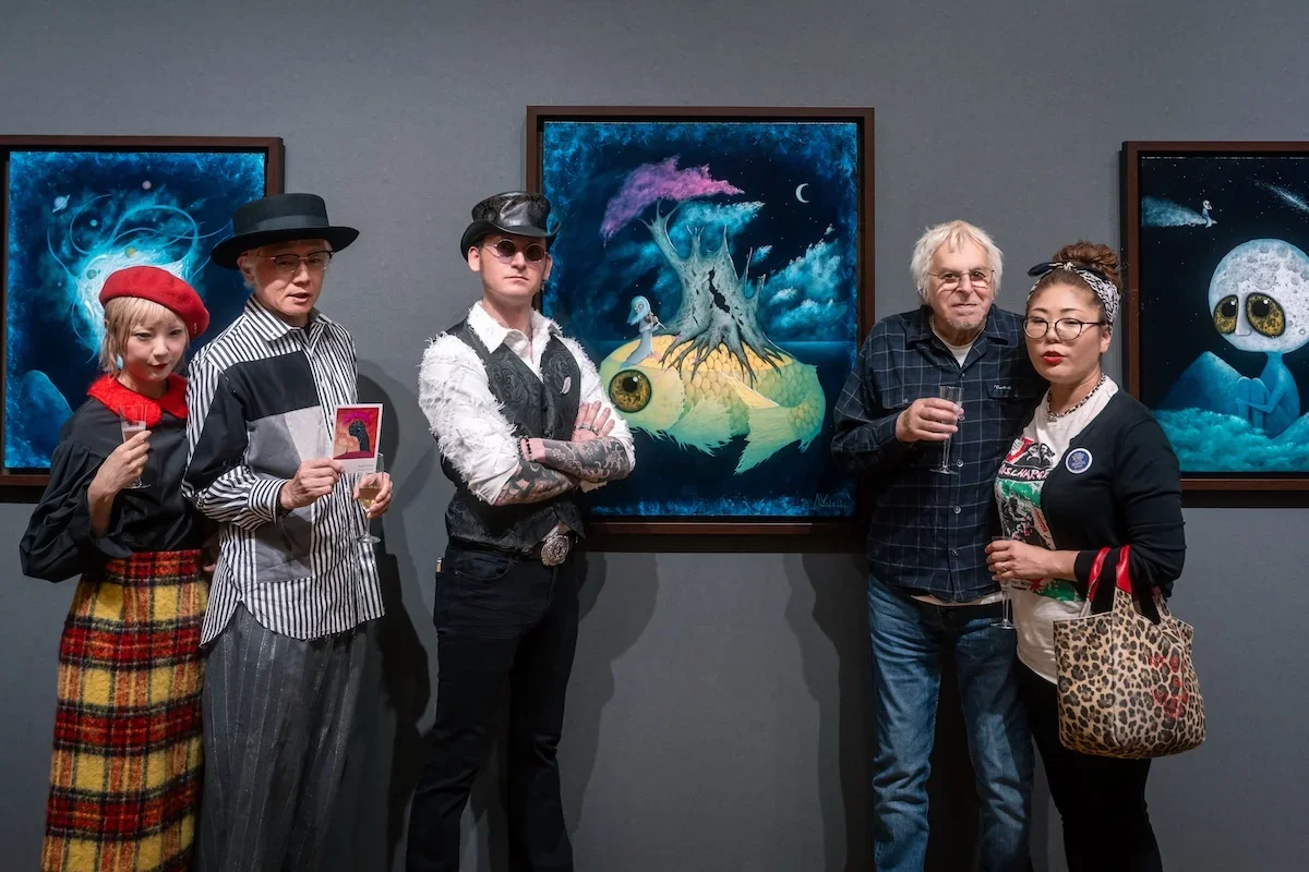August Vilella
---
Guests gather beneath a vibrant painting of a fantastical blue-eyed creature at August Vilella's exhibition, capturing the social atmosphere and artistic character of the gallery opening.