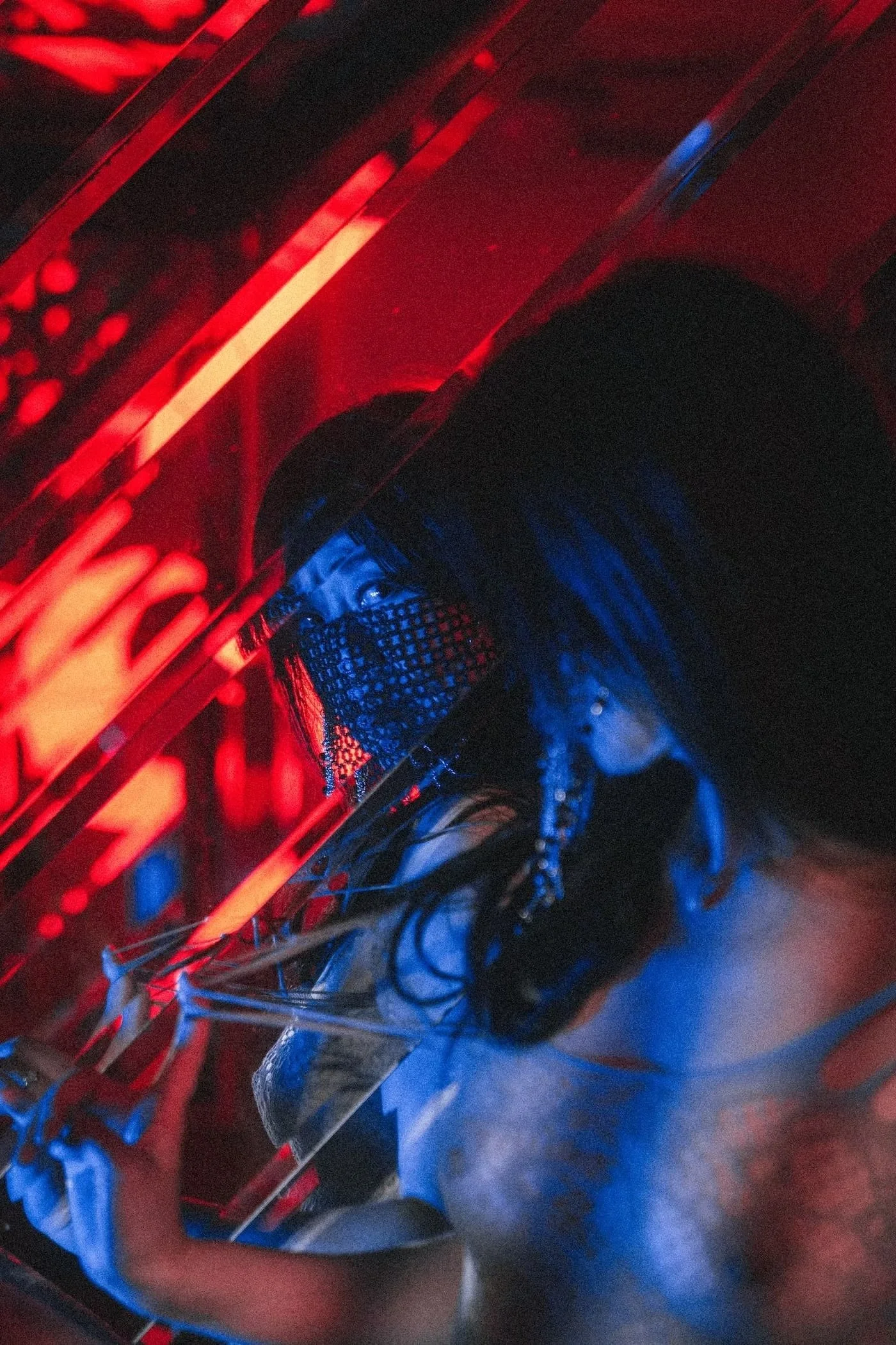 Close-up of a person working on a computer with red and blue LED lighting, showing a black gaming headset and a mechanical keyboard.