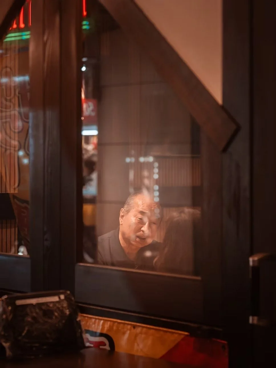 A man having a conversation with a woman in a restaurant seen through a glass window.