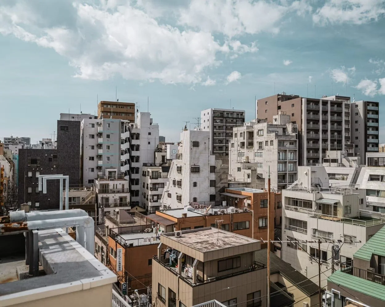 A cityscape with multiple residential and commercial buildings under a partly cloudy sky.