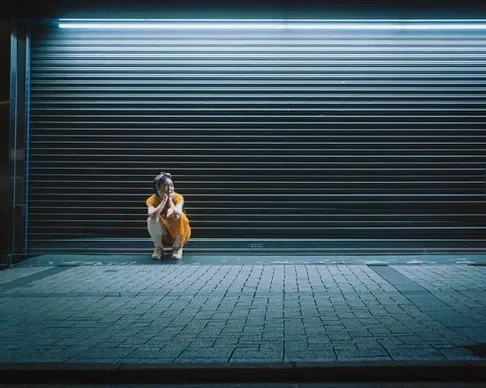 A photographer crouching against a backdrop of a shuttered shop, taken during the Tekumi Photowalks workshop street photography.