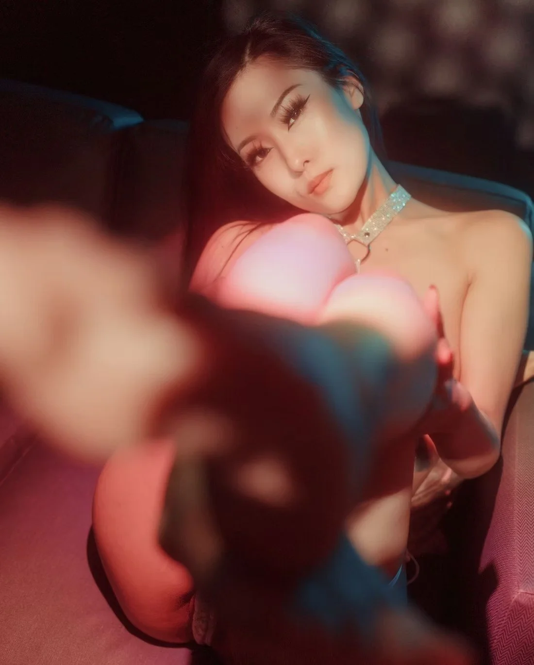 A woman holding a rose with soft pink and green lighting, gazing into the camera. Boudoir Photography by Tokyo Photographer Deniz Demir. Japan.